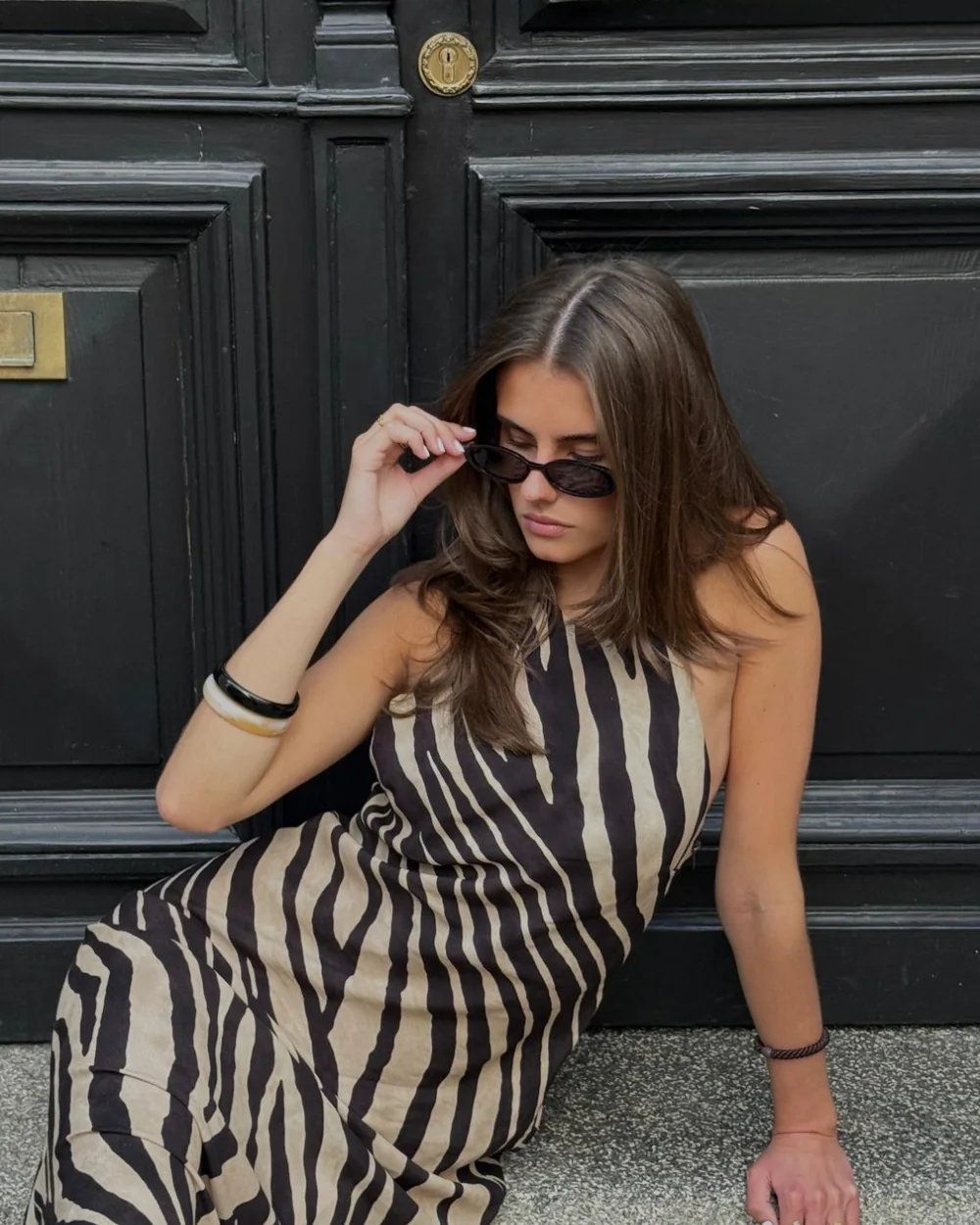 Jule im Zebrakleid mit Sonnenbrille auf einer Treppenstufe vor einer schwarzen Tür